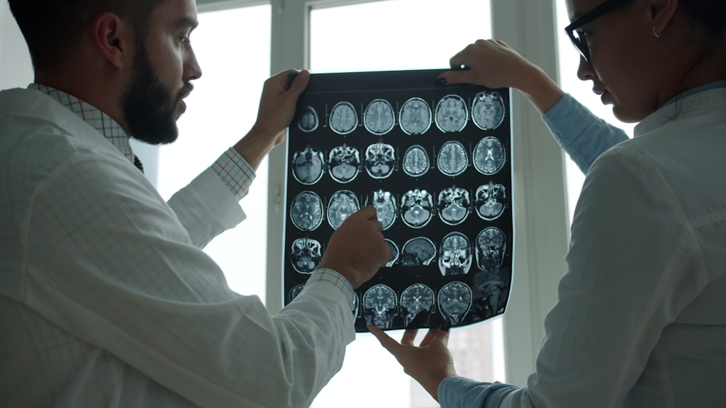 Nova técnica cirúrgica da Neuralink reduz riscos do procedimento de implante médicos analisando exame de ressonância do cérebro para cirurgia de implante