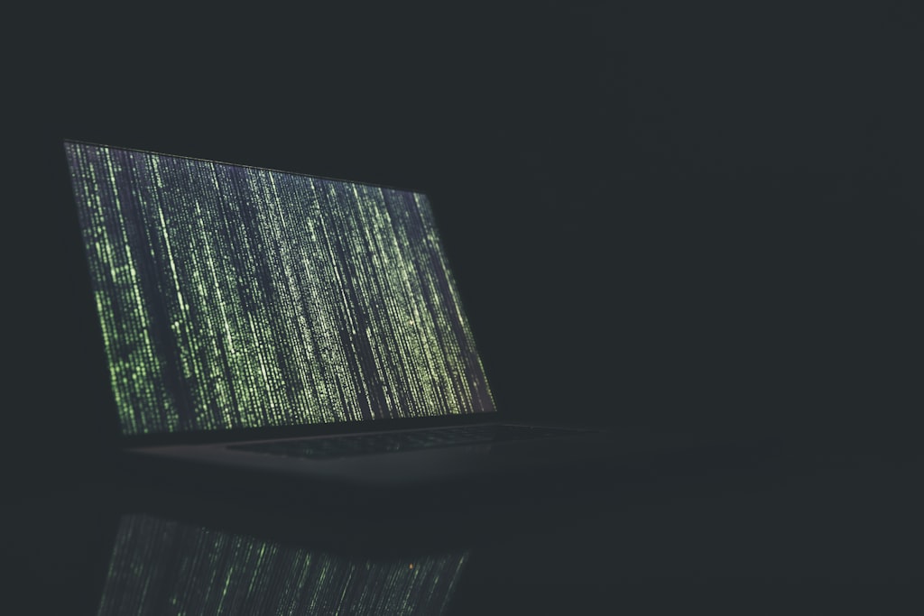Laptop preto e cinza ligado exibindo código, representando o incidente de segurança da OpenAI